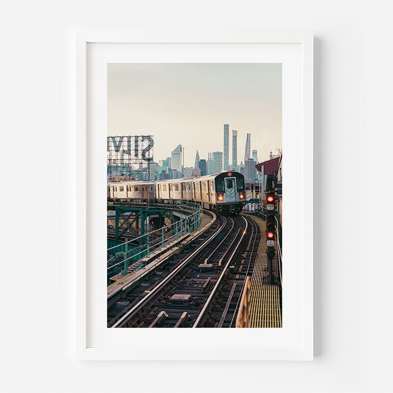 Framed photograph of a train on tracks with a city skyline in the background