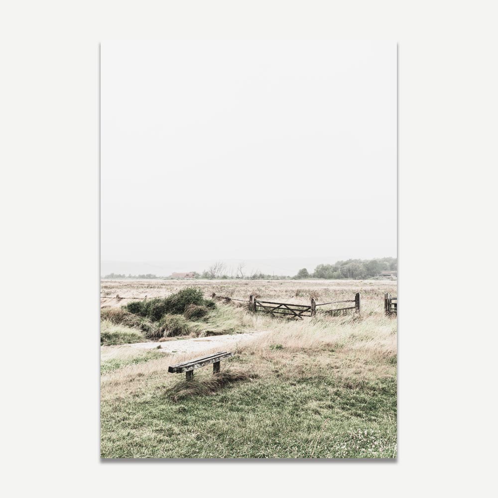 A photograph depicting a serene countryside scene with a fence, farmland, and an old English-style house in the distance. The sky is moody with white clouds and rain.