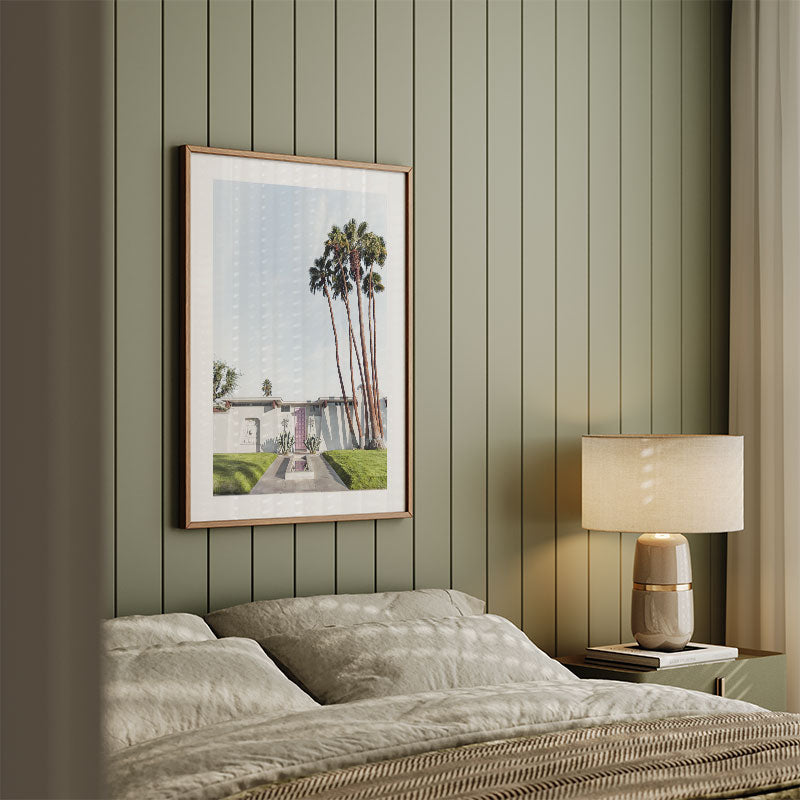 Bedroom with a framed picture of palm trees on a striped wall