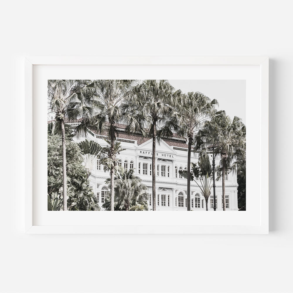 Art print of Raffles Hotel with a focus on the building's facade surrounded by palm trees, predominantly in shades of green and white.