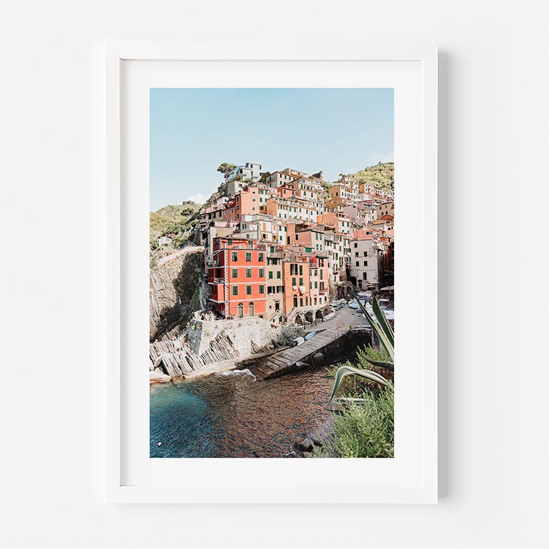 Framed photograph of a coastal town with colorful buildings and a clear blue sky.