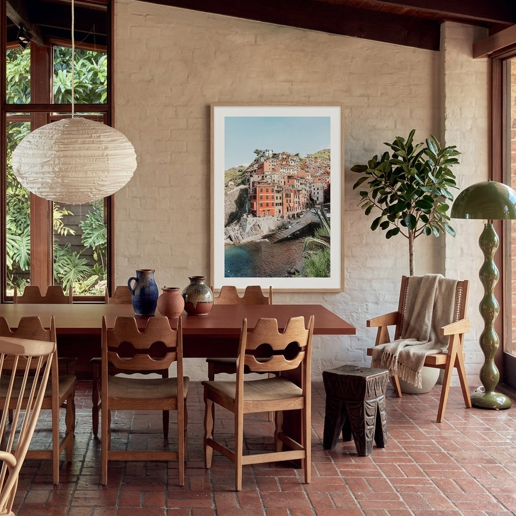 Dining area with wooden table and chairs, framed picture on wall, and potted plant.