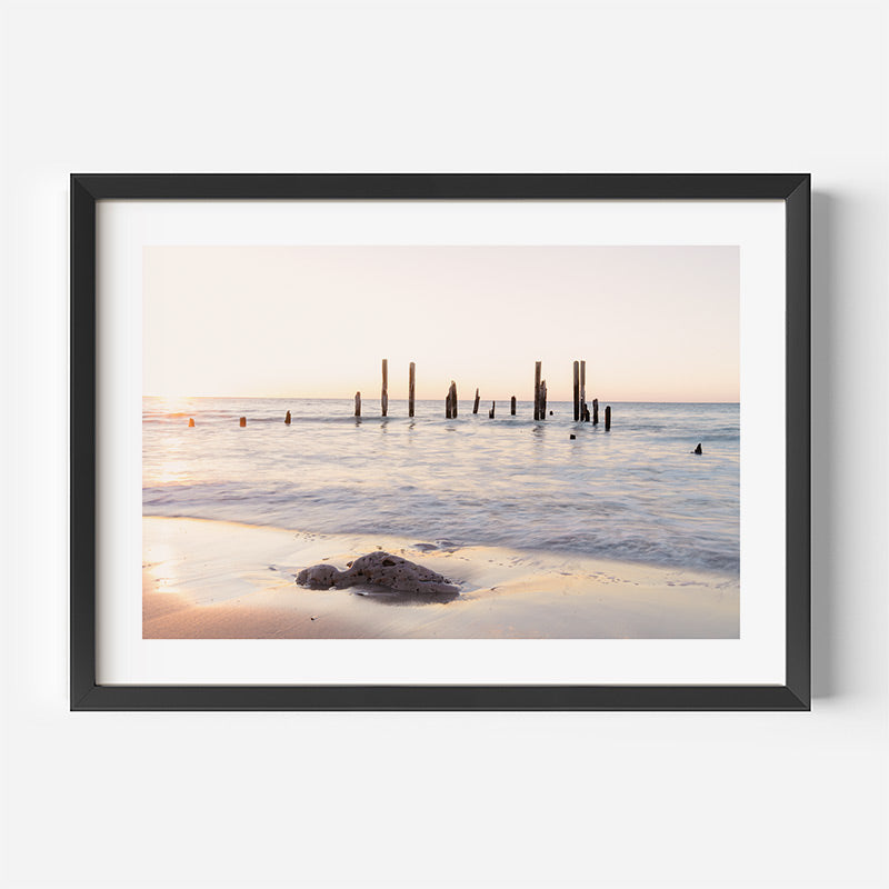 Framed photograph of a beach scene with a sunset or sunrise over water.