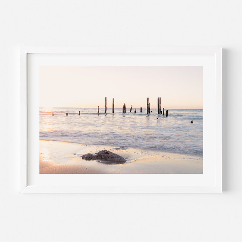 Framed photograph of a beach scene with a sunset or sunrise over water and sand.