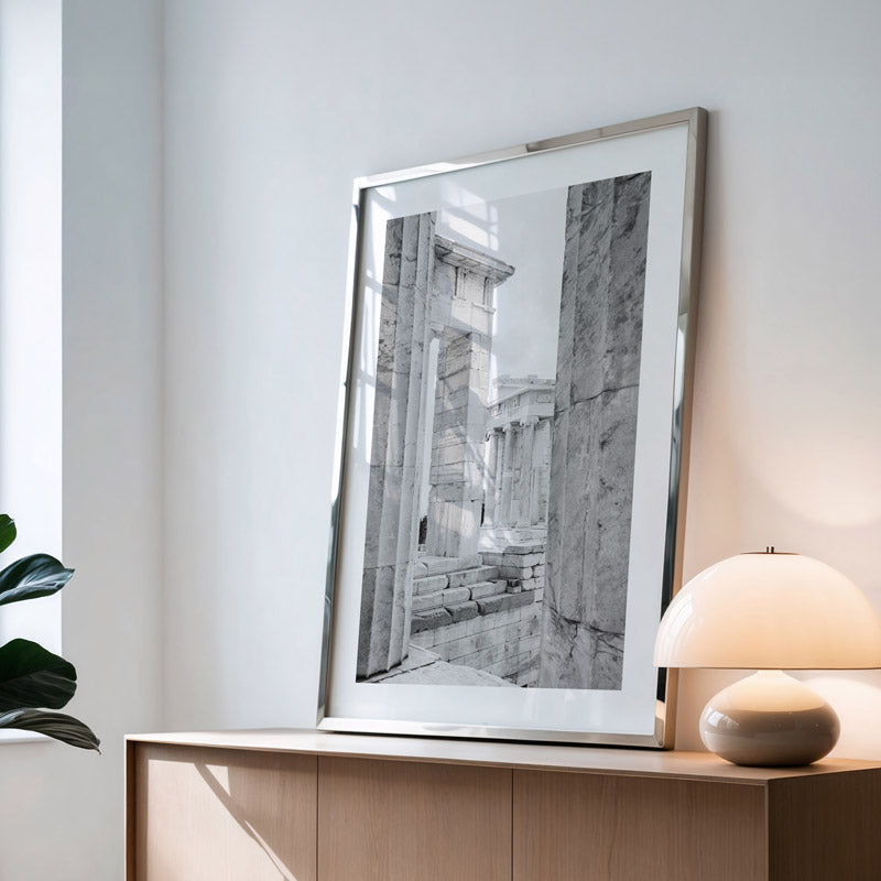 Framed black and white artwork on a wooden console table with a lamp and plant.