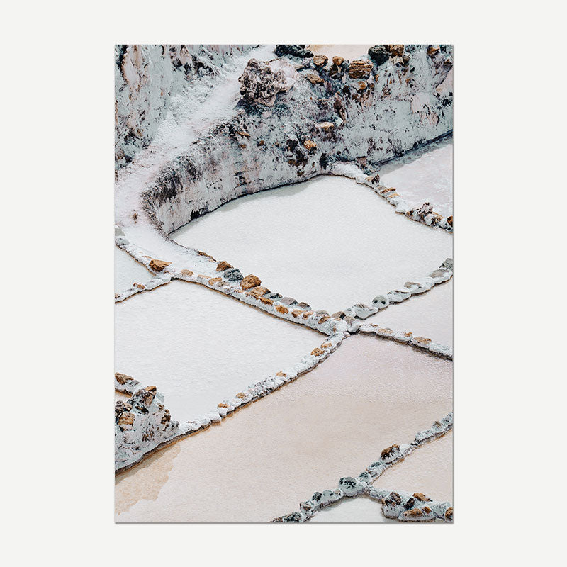 Salt evaporation ponds with salt crystals on the surface, surrounded by a rocky landscape.