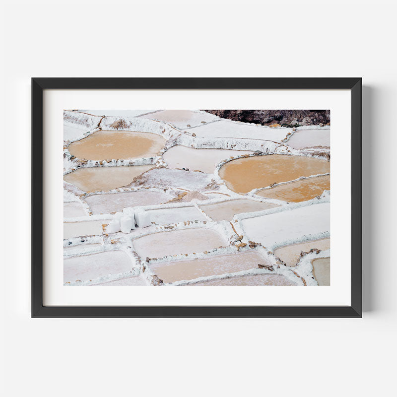 Framed photograph of salt pans with a black frame on a white wall