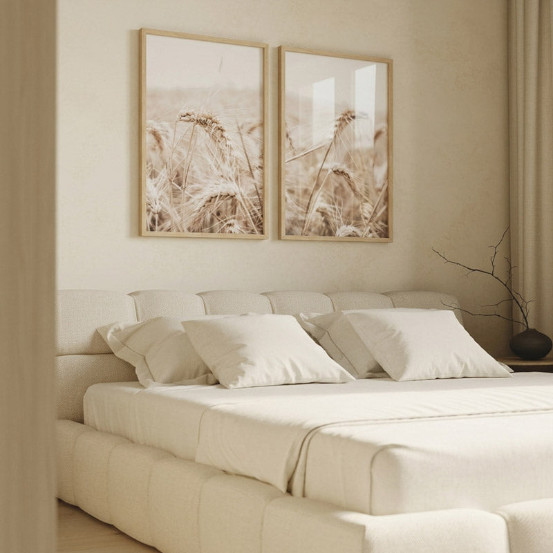 Neatly made bed with beige bedding and pillows in a room with framed artwork on the wall.