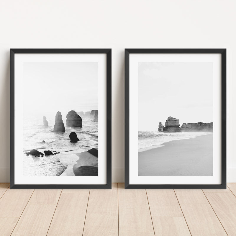 Two framed black and white beach prints on a wooden floor.