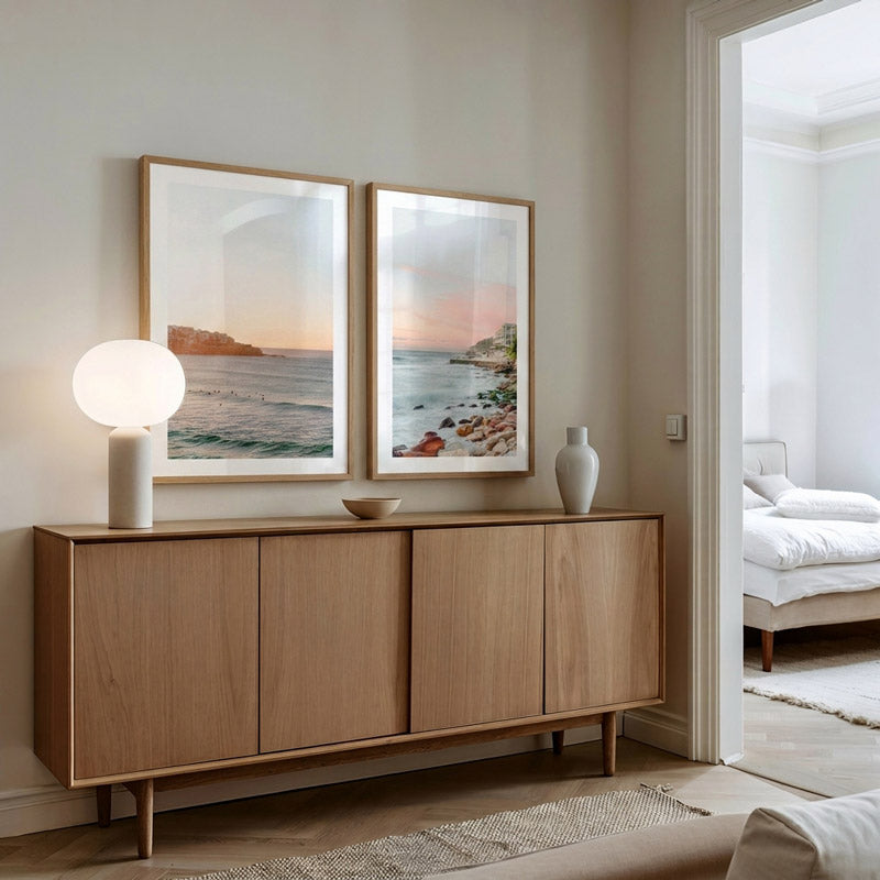 Modern living room with wooden sideboard, lamp, and wall art.