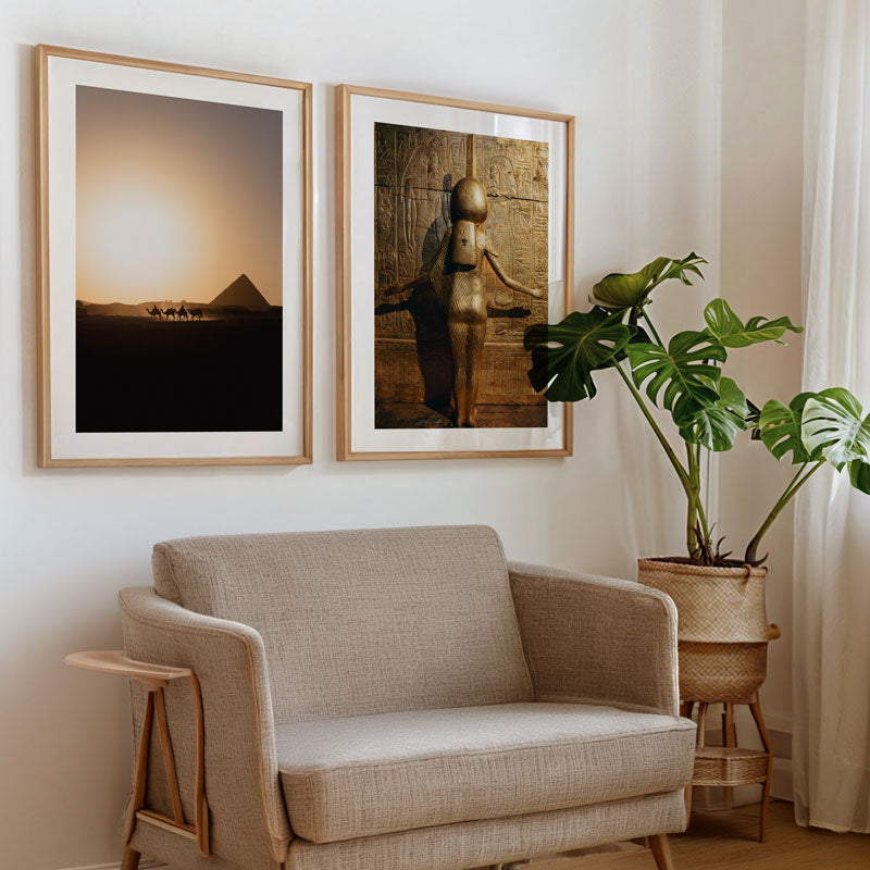 Beige armchair in a room with two framed artworks on the wall and a potted plant.