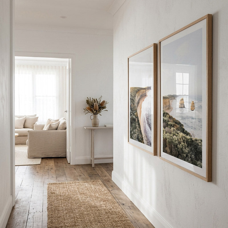 Modern interior with two framed artworks on a white wall, leading to a living room.