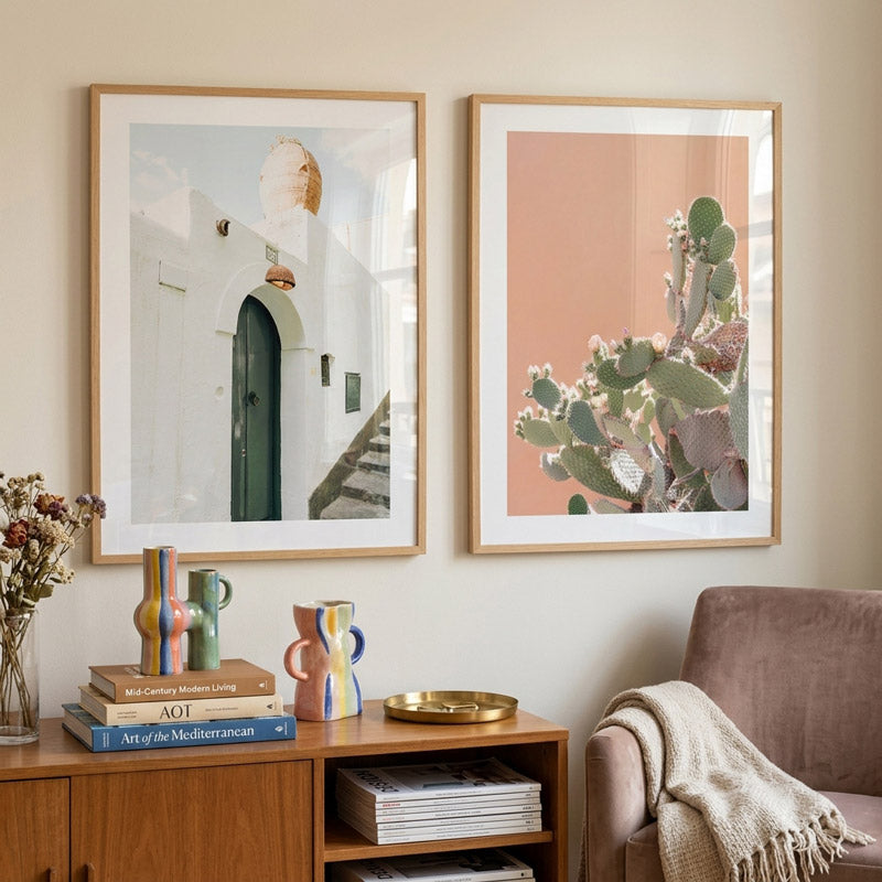 Two framed artworks on a wall above a wooden side table with decorative items.