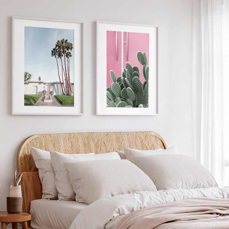 Two framed prints above a bed with a wicker headboard.