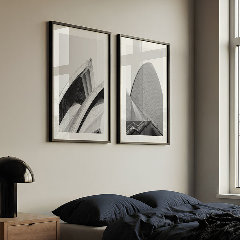 Two framed artworks on a wall above a bed in a bedroom setting.