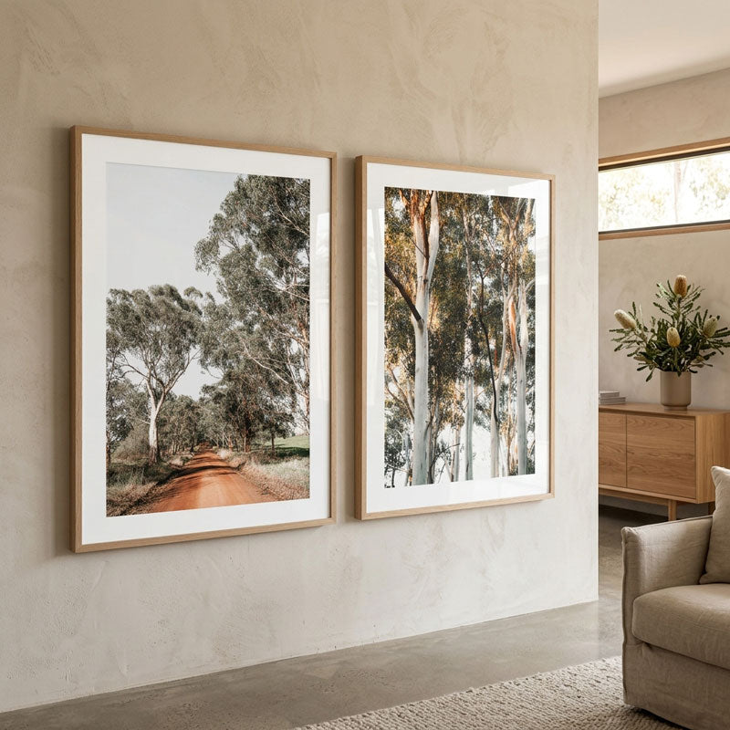 Two framed prints of trees on a wall in a living room.