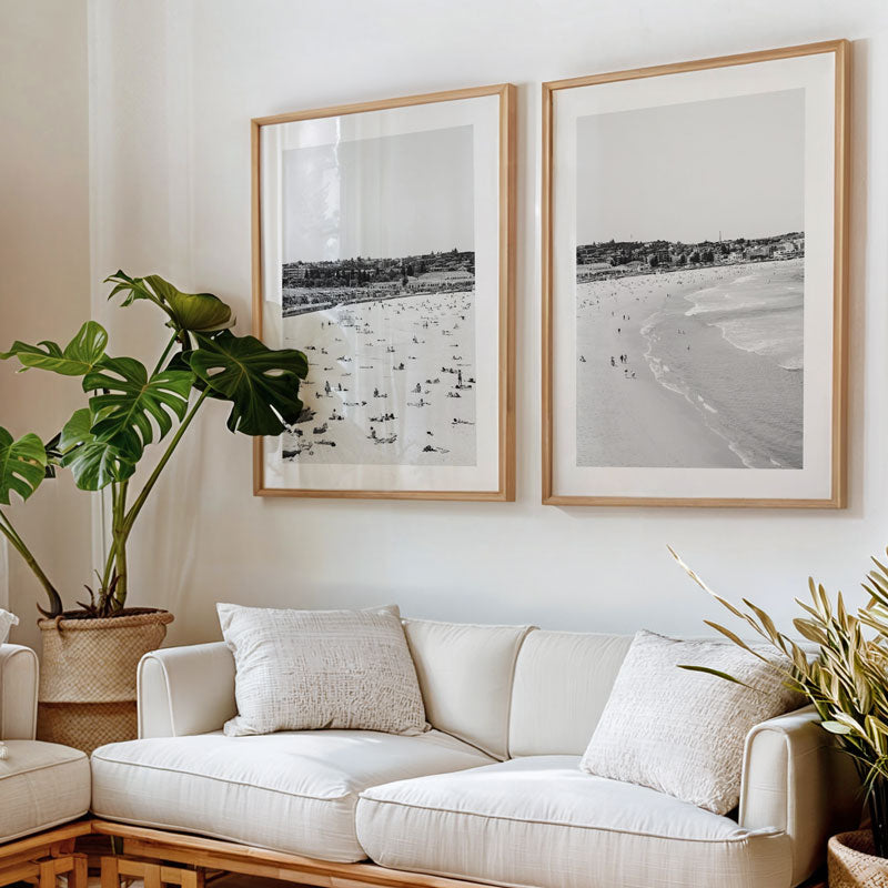 Living room with a white sofa, framed beach photos, and indoor plants.