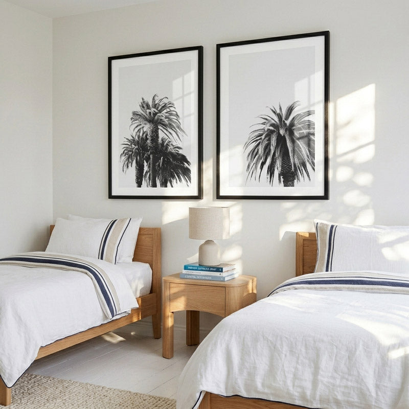 Two beds in a bedroom with palm tree prints on the wall.