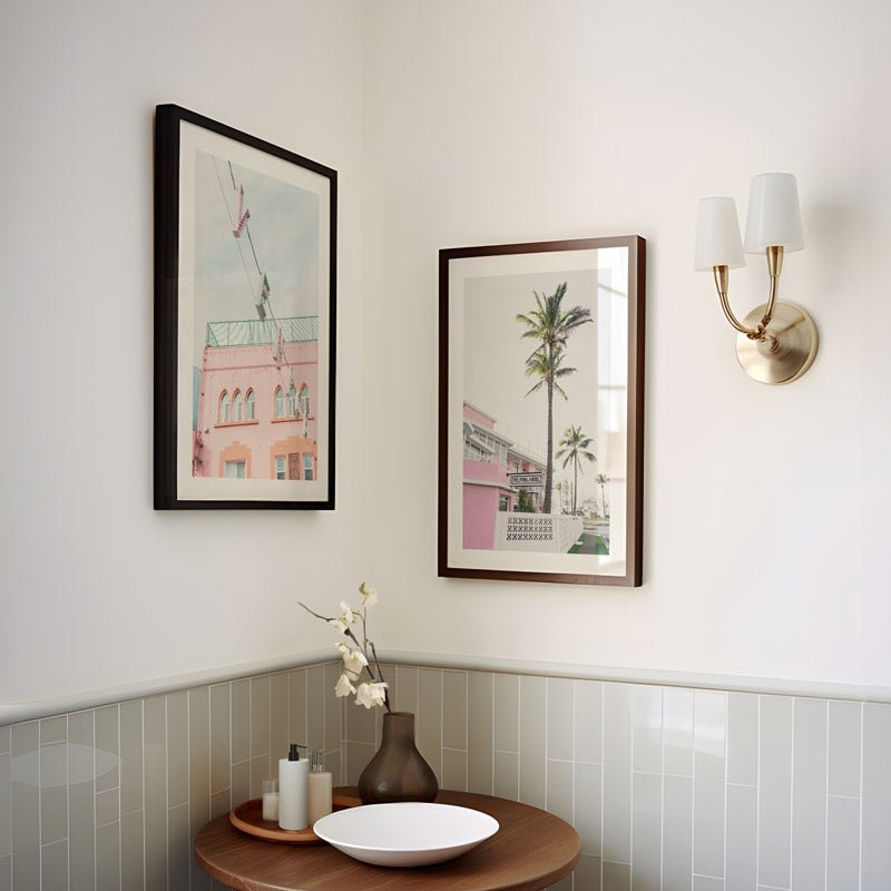 Two framed pictures on a wall with a small table and decorative items below.
