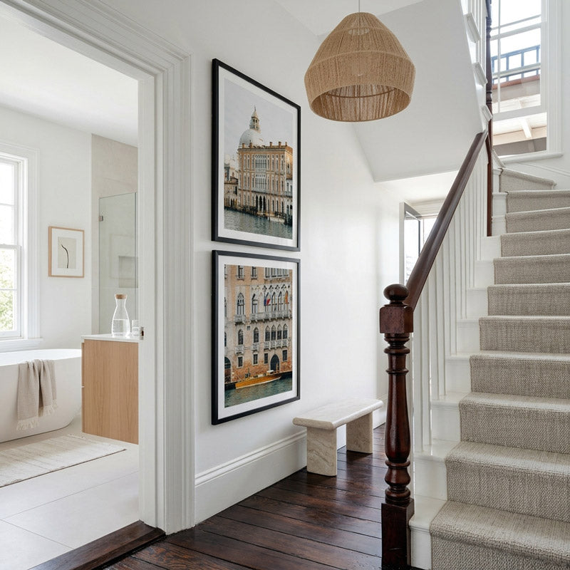 Staircase with wooden handrail and framed pictures on a white wall