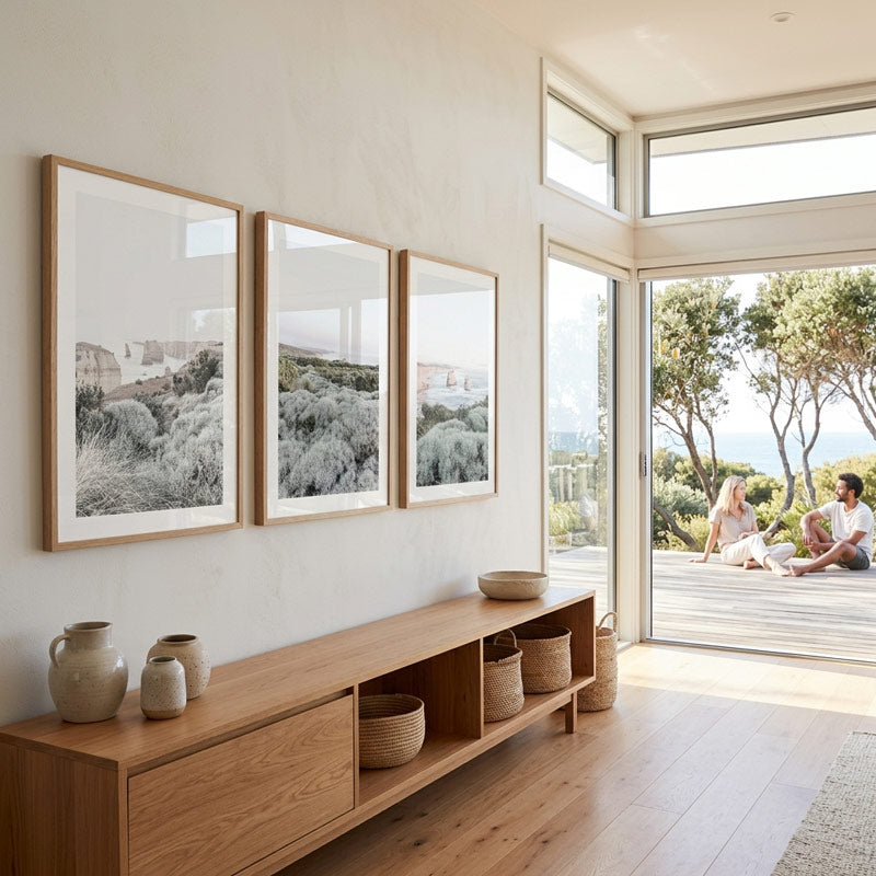 Modern living room with wooden furniture, framed artwork, and a view of people on a patio.