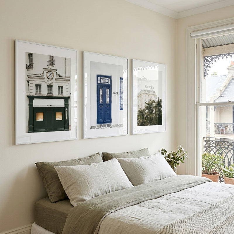 Bedroom with framed pictures on the wall and a bed with pillows and blanket.