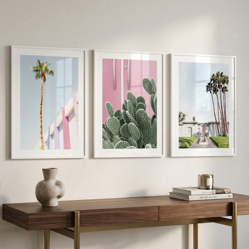 Three framed artworks on a wall above a wooden console table with decorative items.