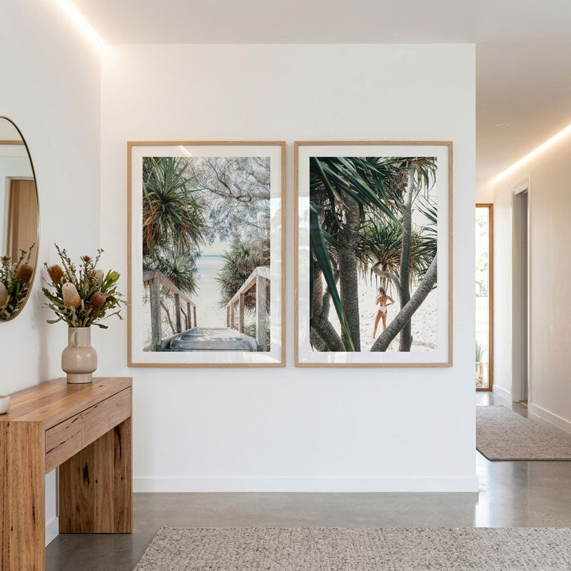 Two framed artworks of a beach scene on a white wall in a modern interior.