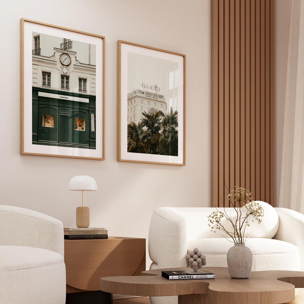 A pair of framed photographs on a wall, depicting a street scene with fashion retail stores.