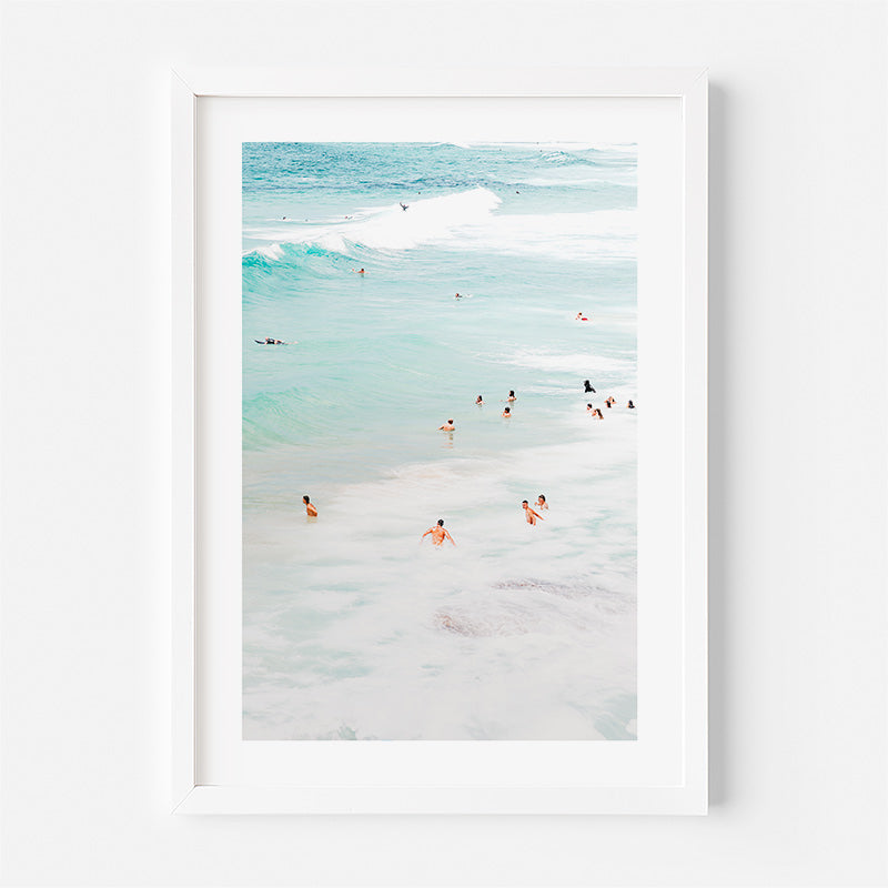 Framed artwork of a beach scene with people in the water.