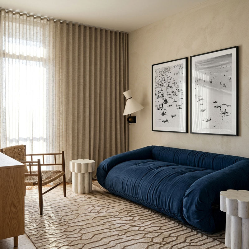 Modern living room with a blue sofa, framed artwork, and neutral decor.
