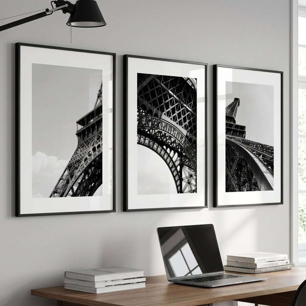 Three framed black and white photos of the Eiffel Tower on a wall above a desk with a laptop.