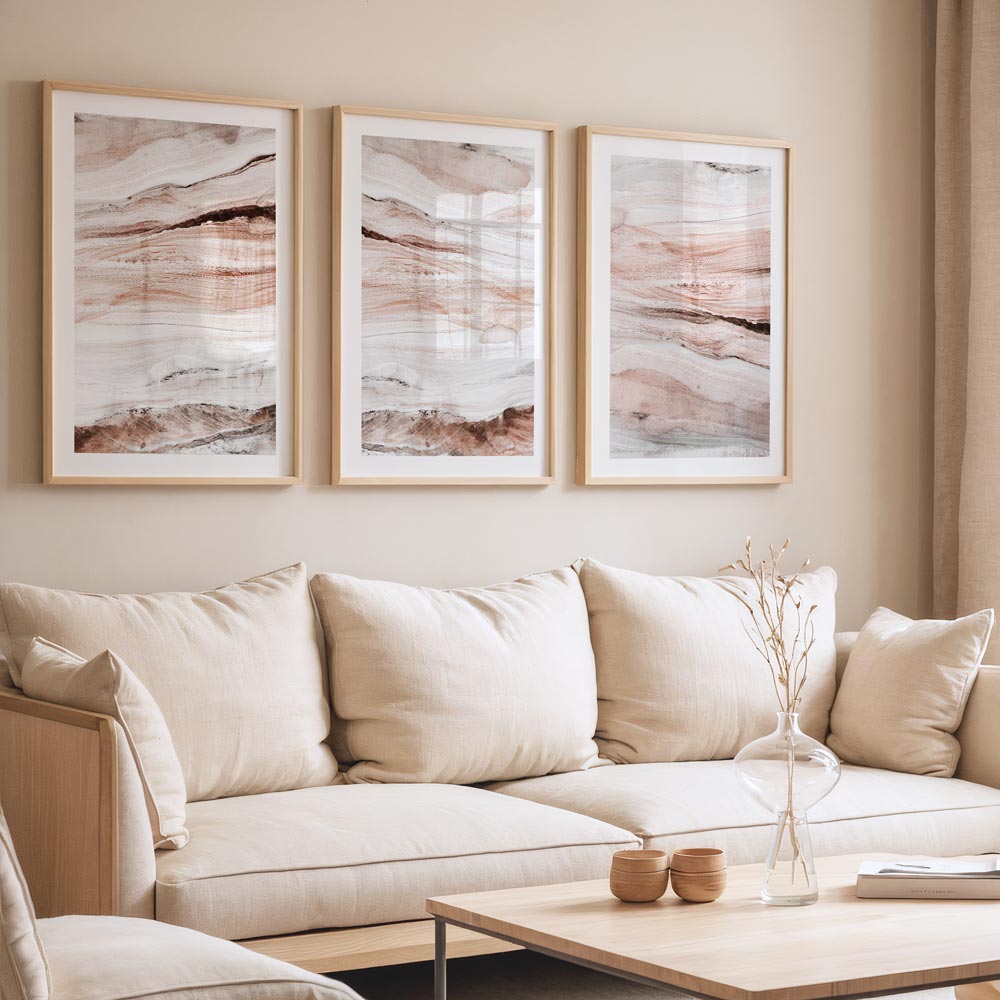 A set of three framed abstract paintings featuring landscape motifs in a home living room setting.