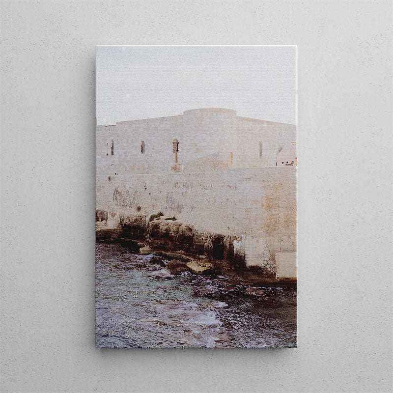 Canvas print of a coastal scene with a stone wall and water on a light gray background