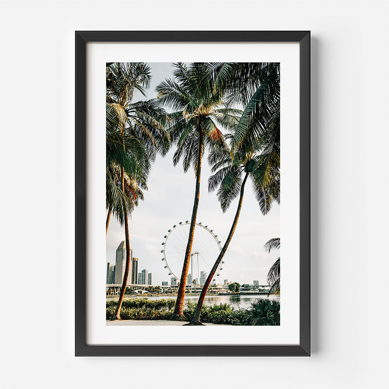 Framed artwork of palm trees with a city skyline and Ferris wheel in the background.