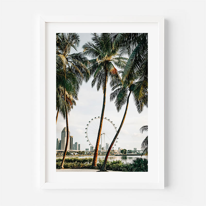 Framed artwork of palm trees with a city skyline and Ferris wheel in the background.
