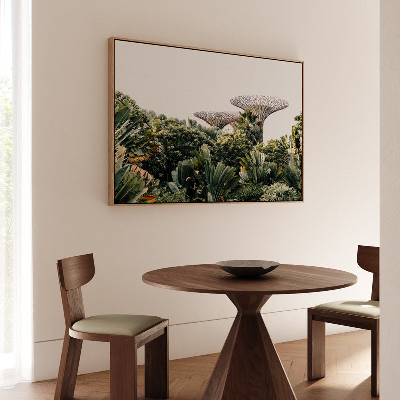 Dining room with a round wooden table and chairs, and a large framed picture of a forest on the wall.