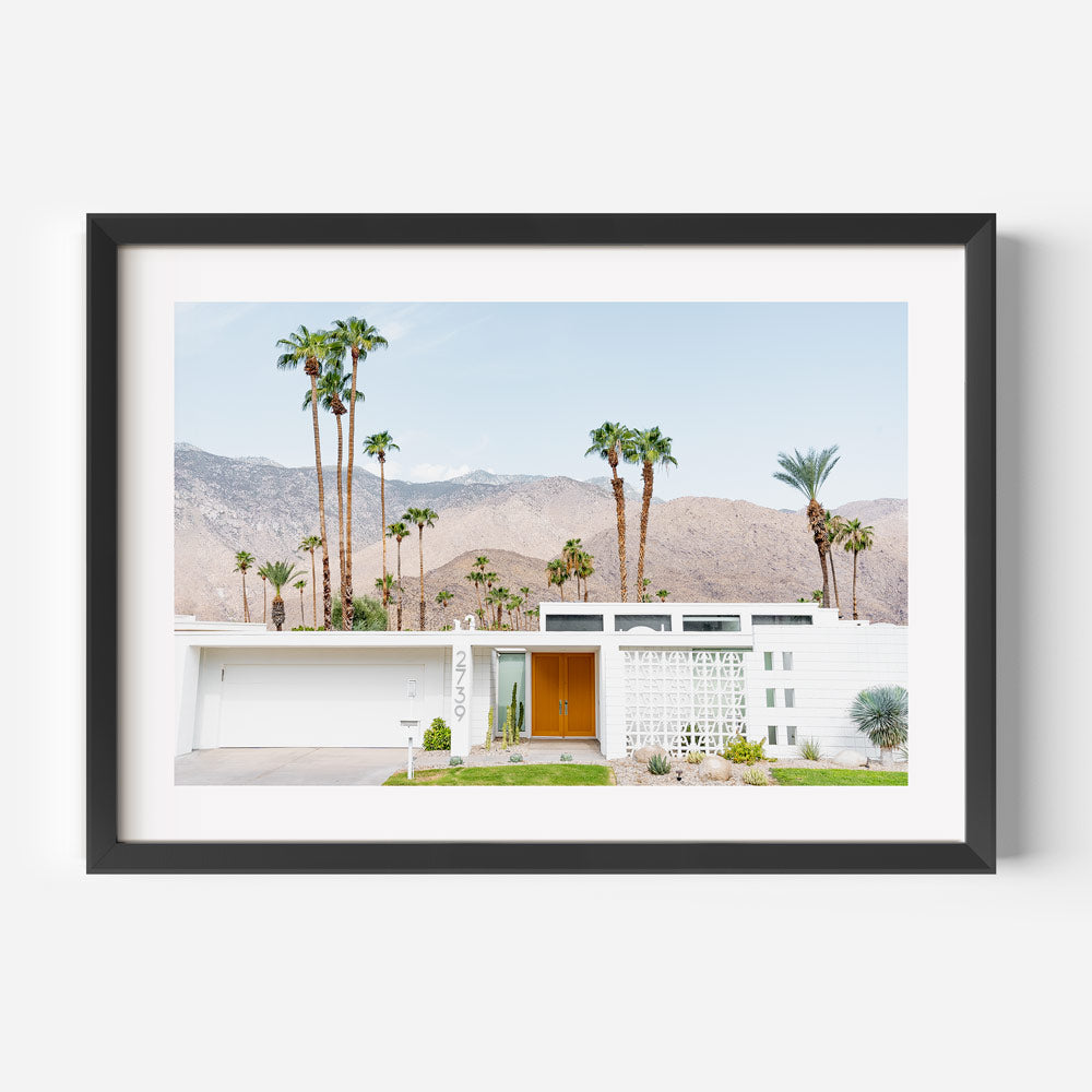 Framed photograph of a modern house with palm trees and mountains in the background