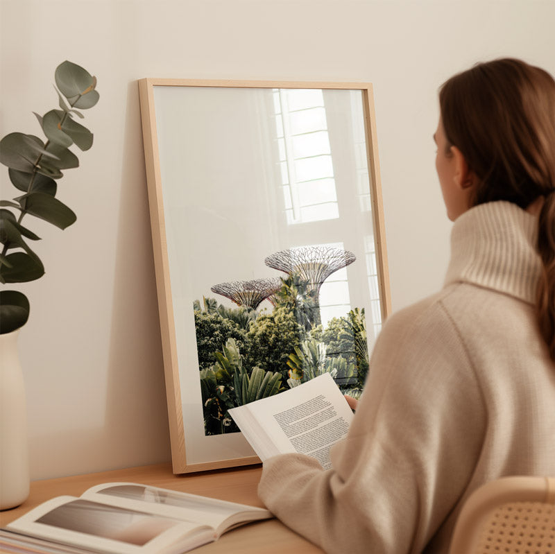 Woman reading a book next to a framed picture of trees