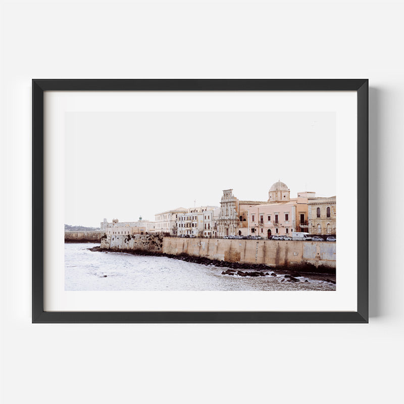 Framed photograph of a coastal cityscape with buildings and water.