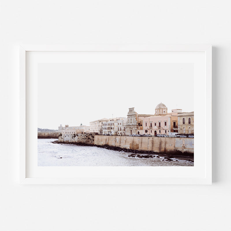 Framed photograph of a coastal cityscape with buildings and water.