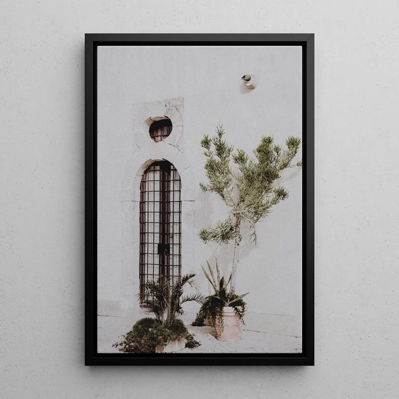 Framed artwork of a building with plants on a light gray wall