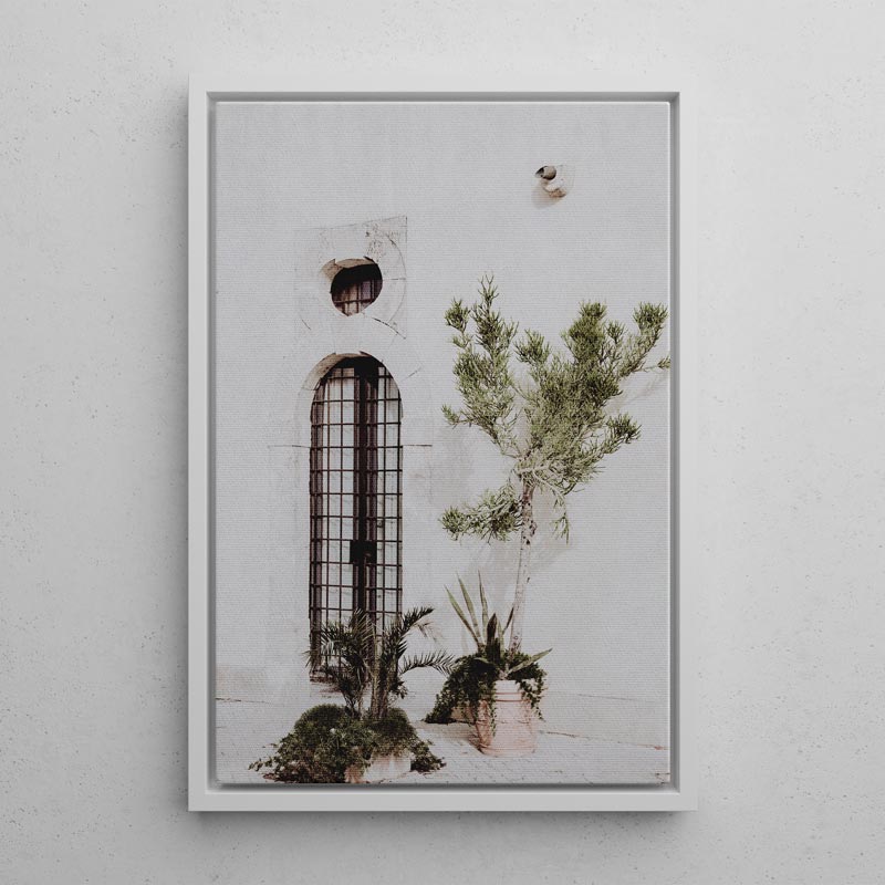 Framed artwork of a building with plants on a light gray wall