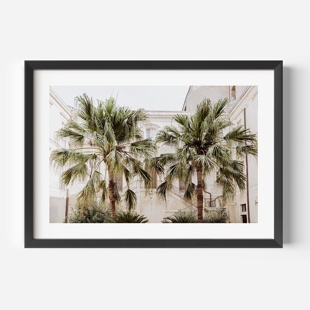 Framed coastal wall art showcasing twin palm trees nestled in a quiet Sicilian courtyard—captured in Syracuse, Italy. This beach scene wall art features soft neutrals, weathered textures, and timeless Mediterranean charm, ideal for beach art for wall and coastal décor.