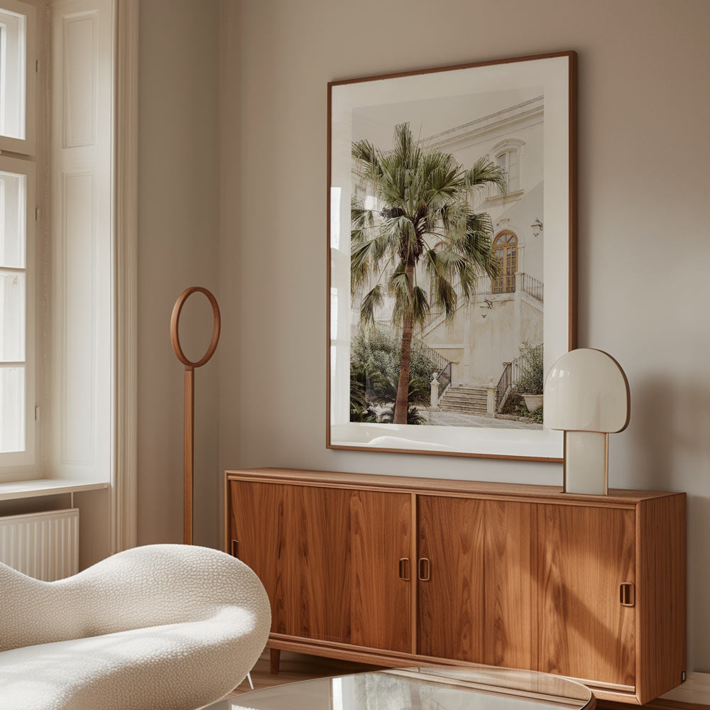 Framed coastal wall art of Sicilian courtyard with a palm tree, styled in a neutral-toned interior with coastal décor – perfect beach wall art for living room or bedroom