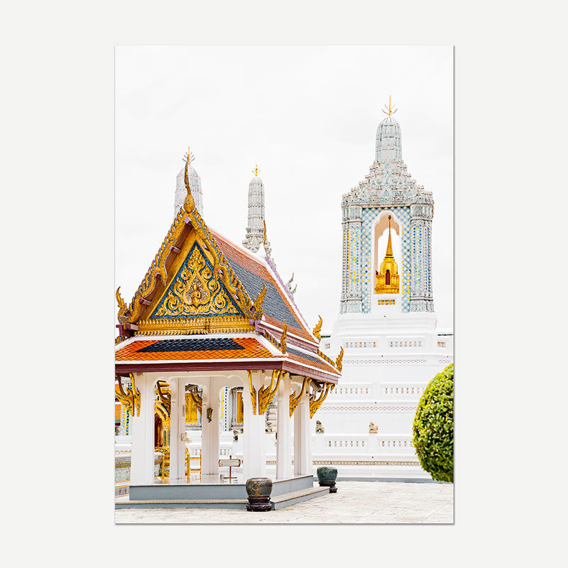A vertical photographic print of a Thai temple courtyard, featuring a golden-roofed pavilion in the foreground and a large white temple tower with gold accents in the background, shown against a light gray backdrop.