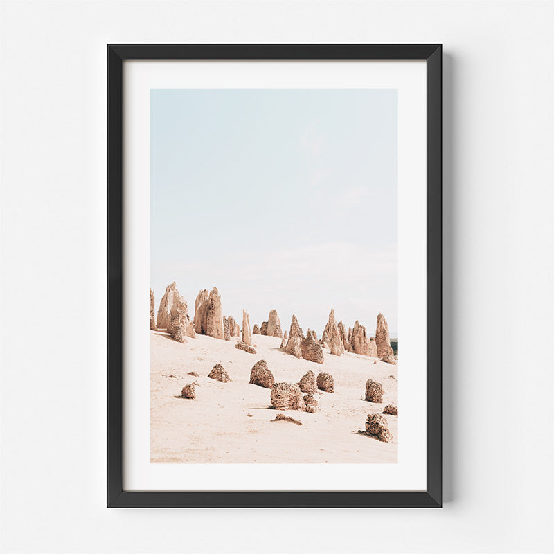 Framed artwork of desert landscape with rock formations on a white wall