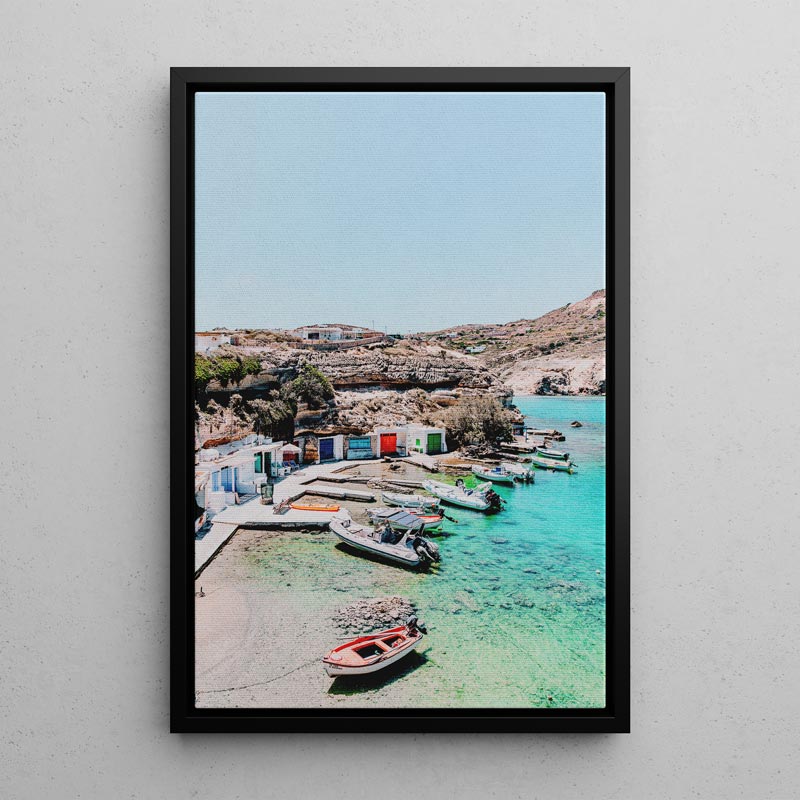 Framed photograph of a coastal scene with boats and a clear blue sky.
