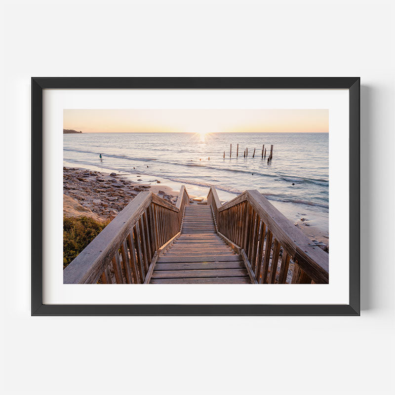 Framed photograph of a wooden staircase leading to a beach at sunset.