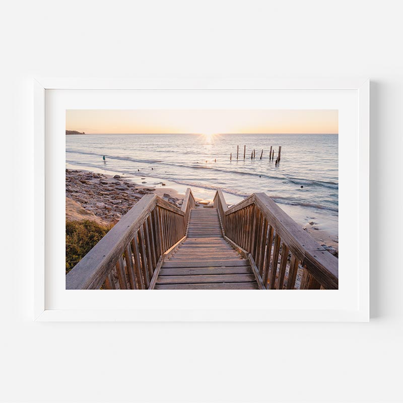 Wooden staircase leading to a beach with a sunset in the background